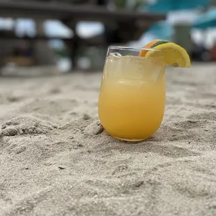 a glass of orange juice on the beach