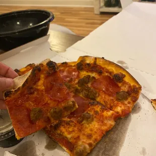 a person taking a slice of pizza