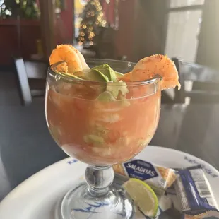 a glass of taqueria with shrimp and lime garnish