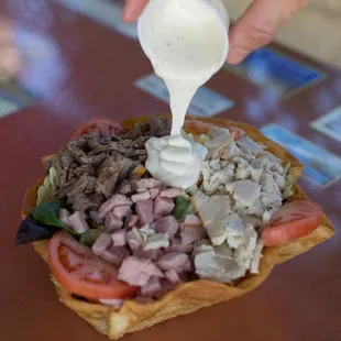 a hand pouring dressing over a pita