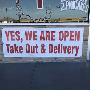 a sign saying yes we are open take out and delivery