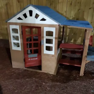 a wooden playhouse with a blue roof