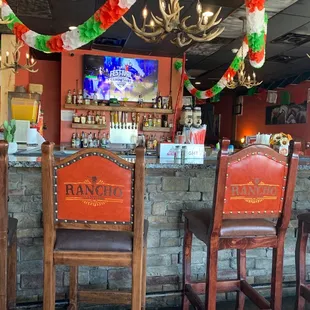 a bar with chairs and a television