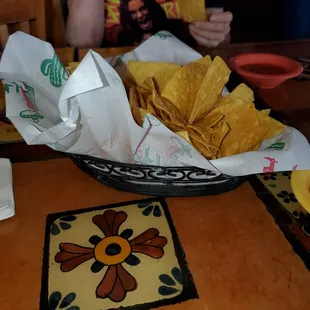 a person sitting at a table with a bowl of chips