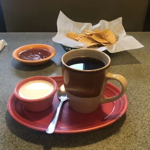 Coffee with milk, chips and salsa.
