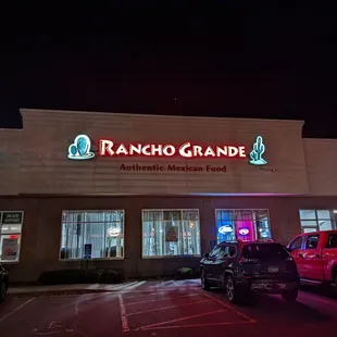 cars parked in front of a restaurant at night