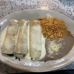 spinach enchiladas with sides of refried beans and rice