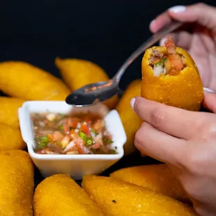 a person holding a spoon and dipping sauce