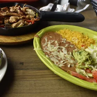 Sizzling fajitas with toppings, refried beans, and rice at Rancho Loco.