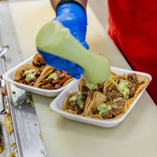  person in a red apron preparing tacoss