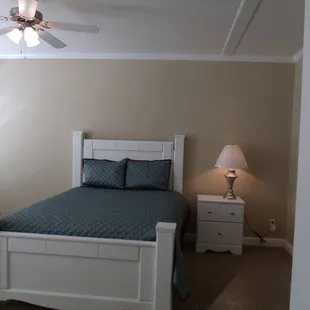 a bedroom with a bed, nightstand, and ceiling fan