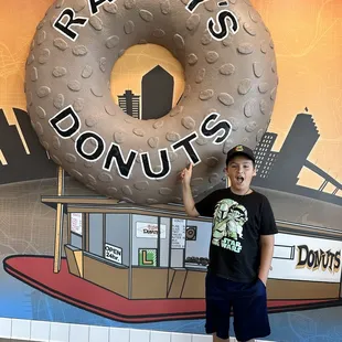 a boy standing in front of a giant donut