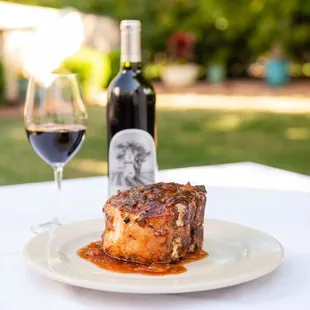 a glass of wine and a plate of steak