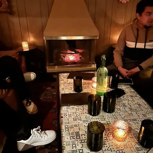 a man and a woman sitting at a table in front of a fireplace