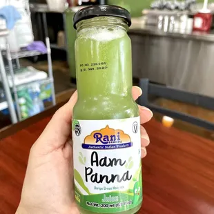 a hand holding a jar of green juice