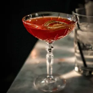 a red cocktail in a coupe glass