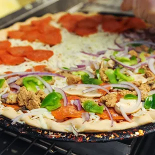 a person putting toppings on a pizza