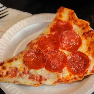 a slice of pepperoni pizza on a paper plate