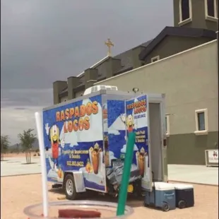 a person holding a drink in front of a food truck