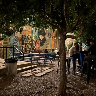people sitting at tables under a tree