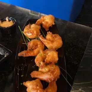 shrimp on a black plate with dipping sauces