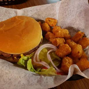 Specialty burger with bacon and cheese and a side of tots
