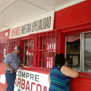 a man and a woman standing outside of a restaurant