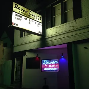 a neon sign for raven lounge