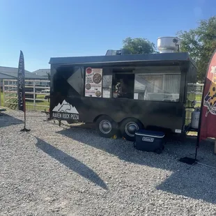 a food truck parked in a gravel lot