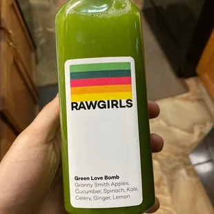 a person holding a bottle of green juice