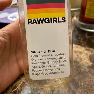 a hand holding a bottle of raw girls