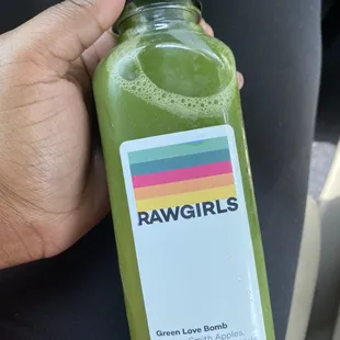 a person holding a bottle of green juice