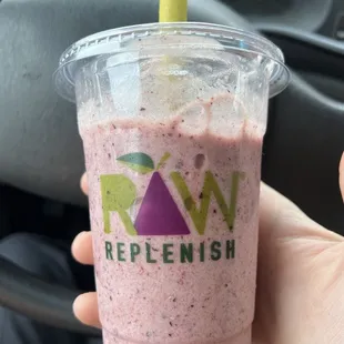 a hand holding a plastic cup with a straw