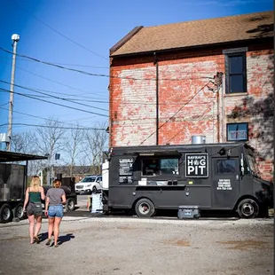 a black food truck parked in front of a red brick building