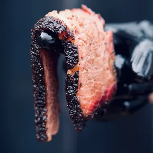 a hand holding a piece of bacon