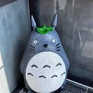 a totoro with a green leaf on its head