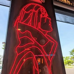 a red neon sign with a man&apos;s face on it