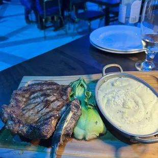 a steak and mashed potatoes on a cutting board