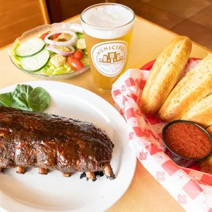 a plate of ribs, breadsticks, and salad