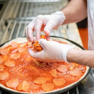 a chef putting toppings on a pizza