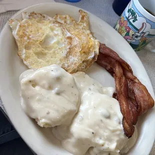 a plate of eggs, bacon and gravy