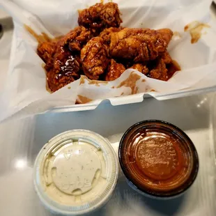 a bowl of sauce and a container of chicken wings