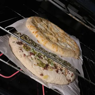 In the oven!  Top: Cheesy garlic bread sticks (medium, 12") Bottom: Boss lady combo pizza (giant, 16")