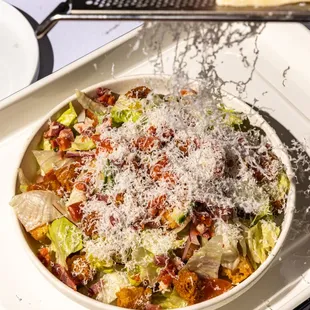 a bowl of salad with parmesan cheese