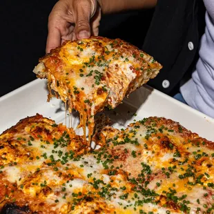 a person taking a slice of pizza