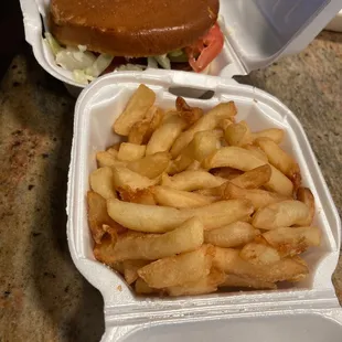 Hot sausage on bun dressed with cheese and a small fries.
