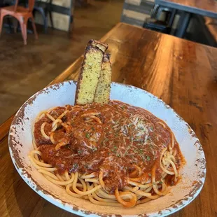 a plate of spaghetti and a piece of bread