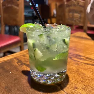 a glass of mojita with a straw and lime garnish