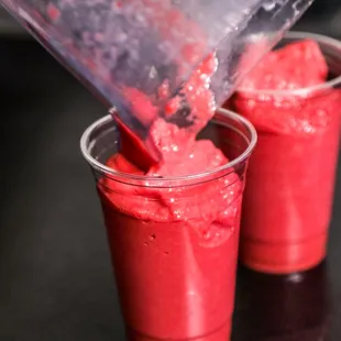 a blender pouring red liquid into two cups