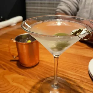 a martini with a green olive garnish